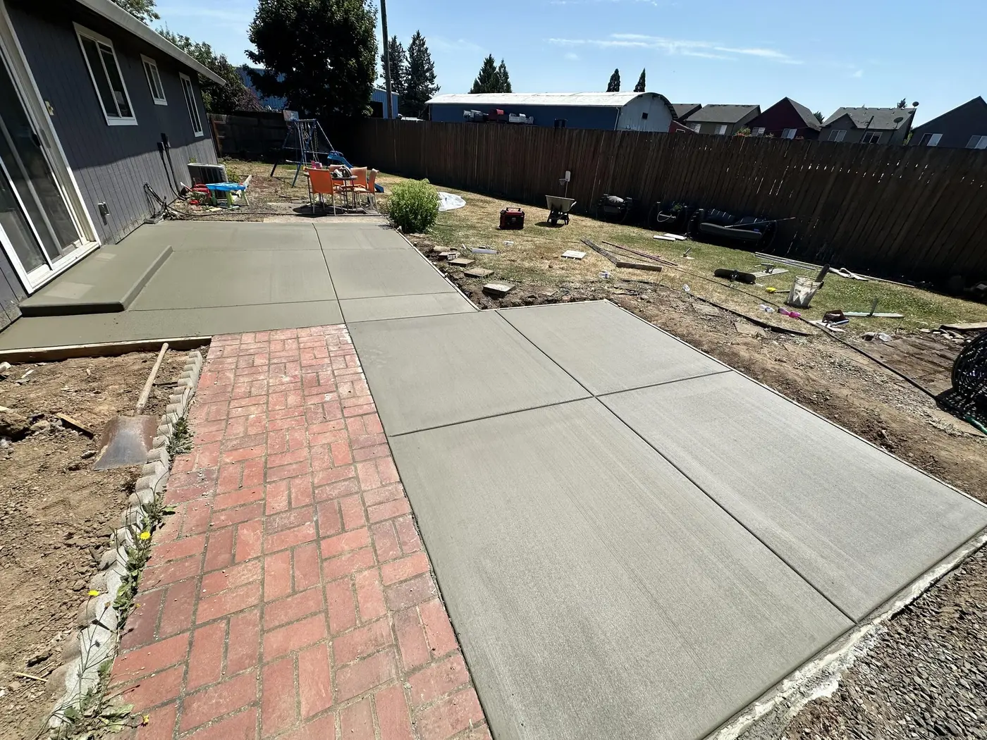 Finished concrete slab beside a house and brick walkway